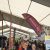 Crowded exhibition hall under a white tent, with tall vertical banners and attendees exploring booths.