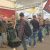 Group of men at an automotive expo examining a green and black car seat display under a red ASN banner at a boothsite.