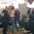Two shoppers examine a car seat at an auto show booth, with several black seats on display beneath a tent.
