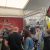 Trade show booth with red RSN banner displaying car seats on display under a white tent, visitors examining products.